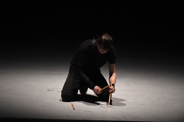 Image of percussionist kneeling with three drums sticks