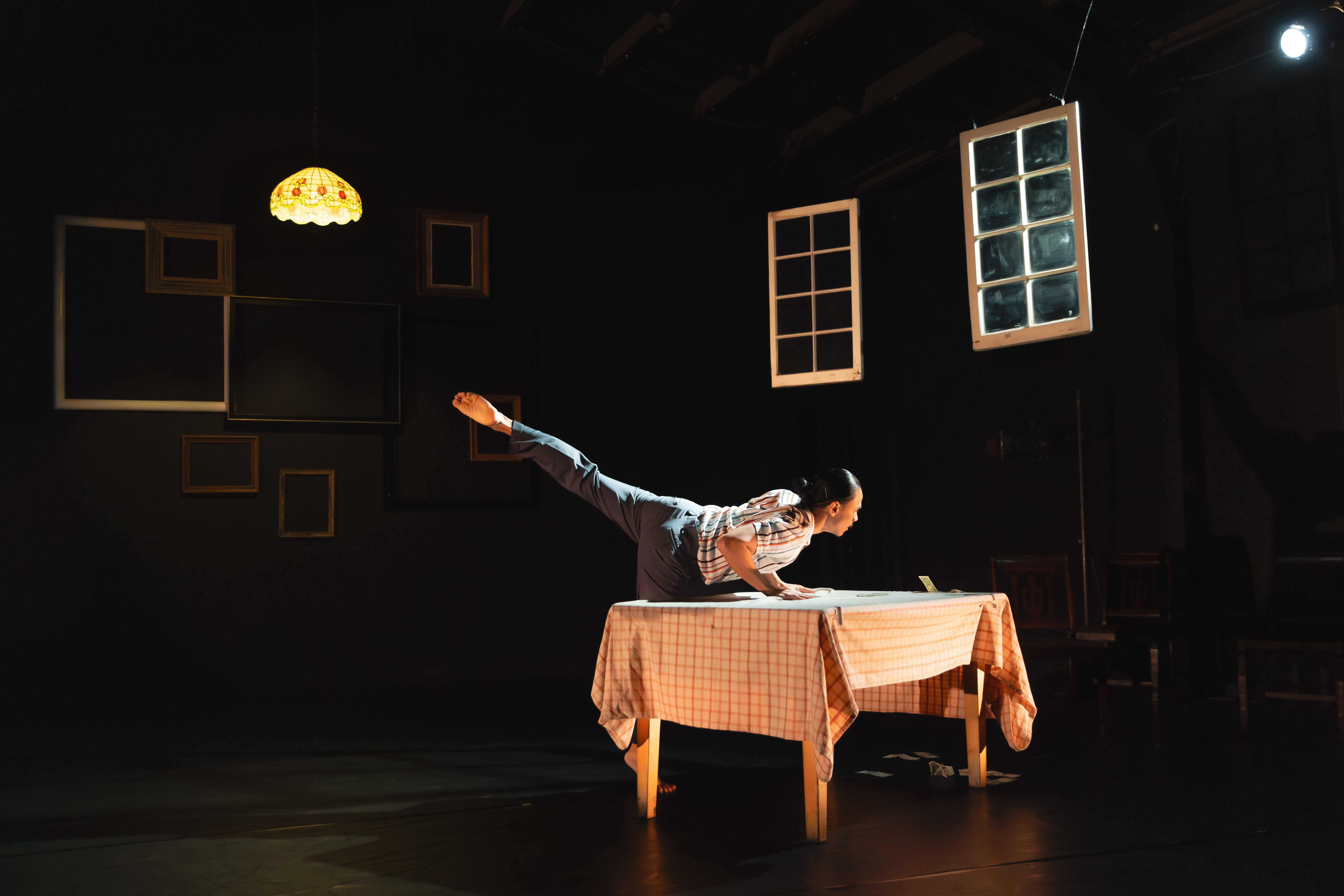 Dancer leaning on a table with his leg extended behind him as he looks at the money on the table.